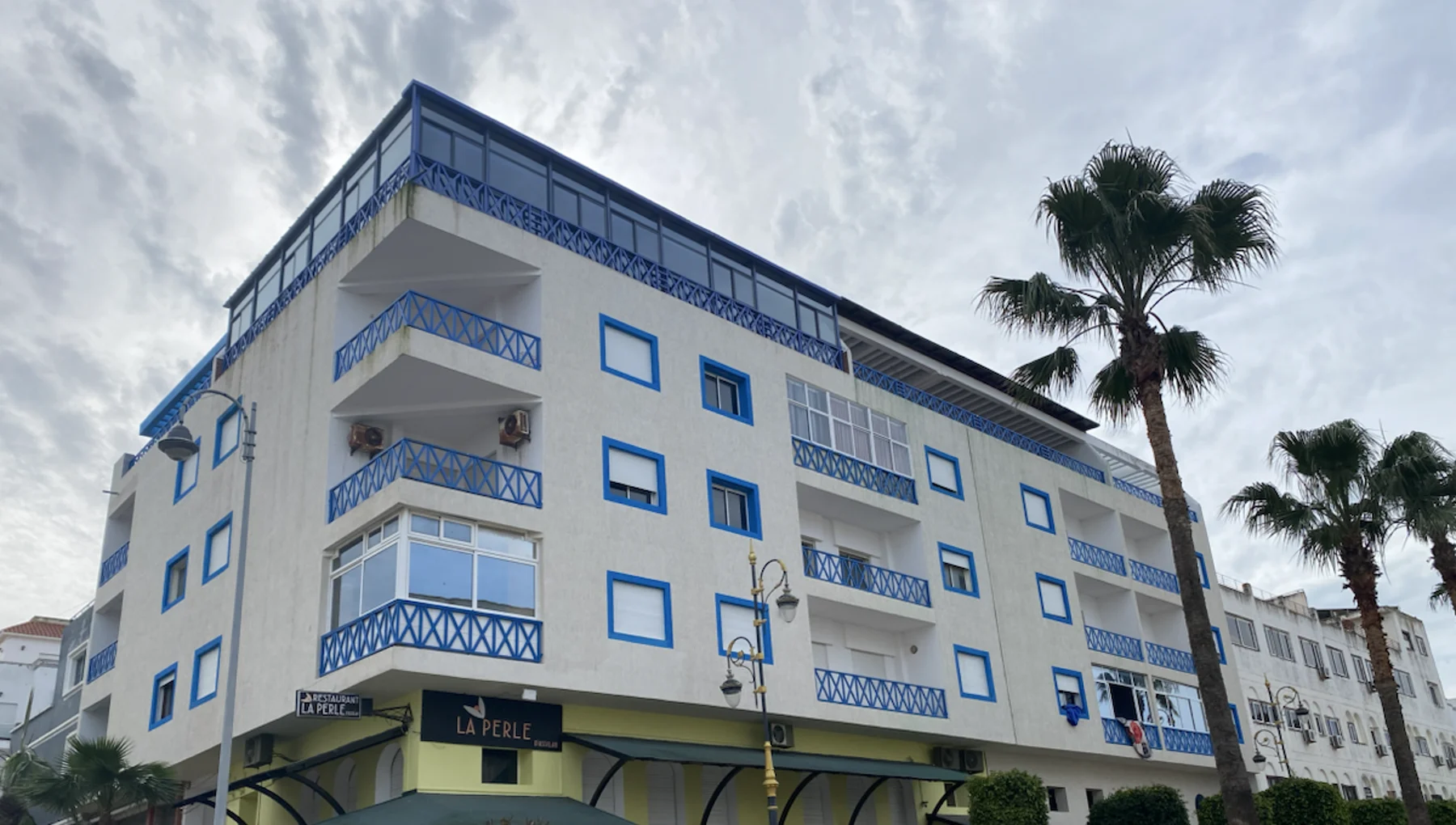 Photographie de 2025 montrant la façade blanche et bleue de La Perle d’Asilah après sa rénovation